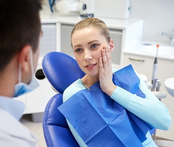 Woman in need of emergency dentistry holding cheek in pain