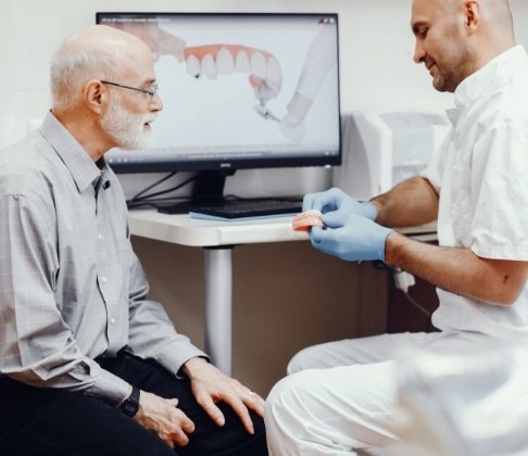 Dentist explaining the four step dental implant process to patient