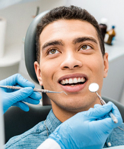 Man in dental chair looking at dentist about to examine his mouth