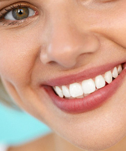 Eye-to-neck closeup of woman smiling with light blue background