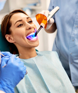 Dentist applying UV light to patient’s new filling