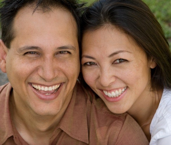 Man and woman sharing healthy smiles after replacing missing teeth