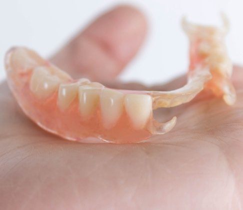 Hand holding partial denture