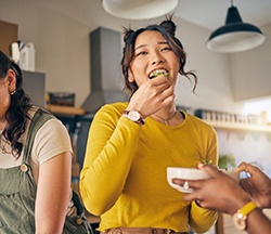 Friends smiling while enjoying meal together at home