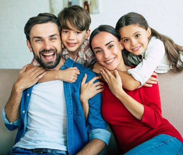 Family of four smiling after preventive dentistry visit