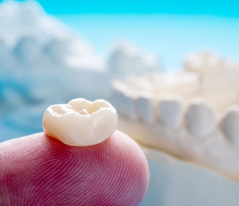 Dental crown resting on fingertip