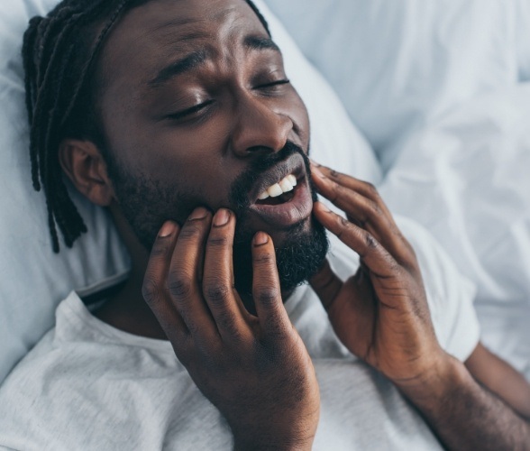 Man in need of T M J therapy holding jaw in pain