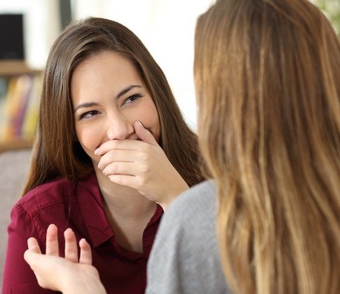 Woman in need of porcelain veneers hiding her smile