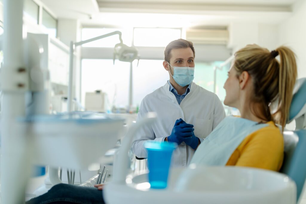 Dentist looking at smiling patient in treatment room